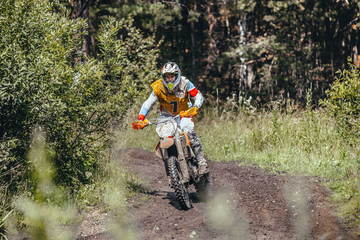 Piloto de enduro por una senda entre el bosque