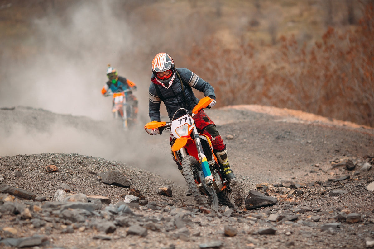 Dos pilotos de enduro en una pista de piedras levantando polvo