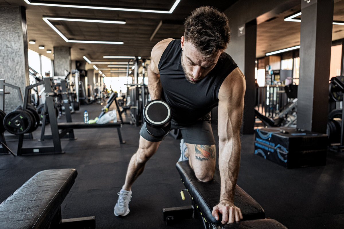 Hombre haciendo remo con mancuerna en un gimnasio