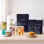 Pack Kitchen: harina de avena, Evocakes, dos bolsas de Evowhey, cinco siropes, crema proteica y shaker, junto a un plato de tortitas